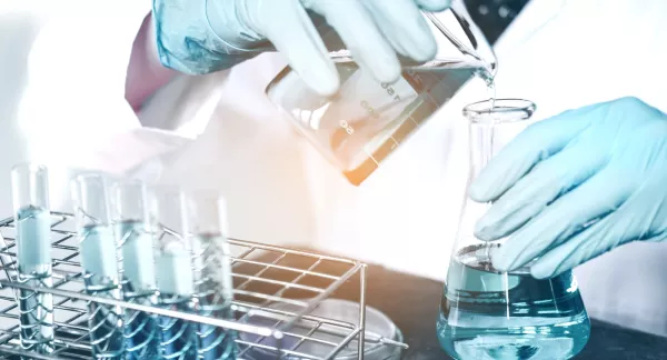 Researcher in lab pouring liquid into a beaker